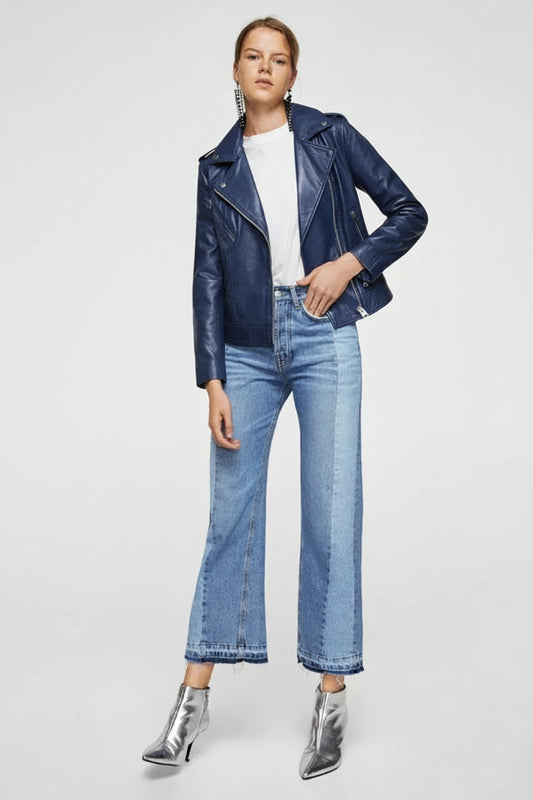 A woman wearing a blue real leather jacket with a standing collar and front pockets, paired with a white top and blue jeans.