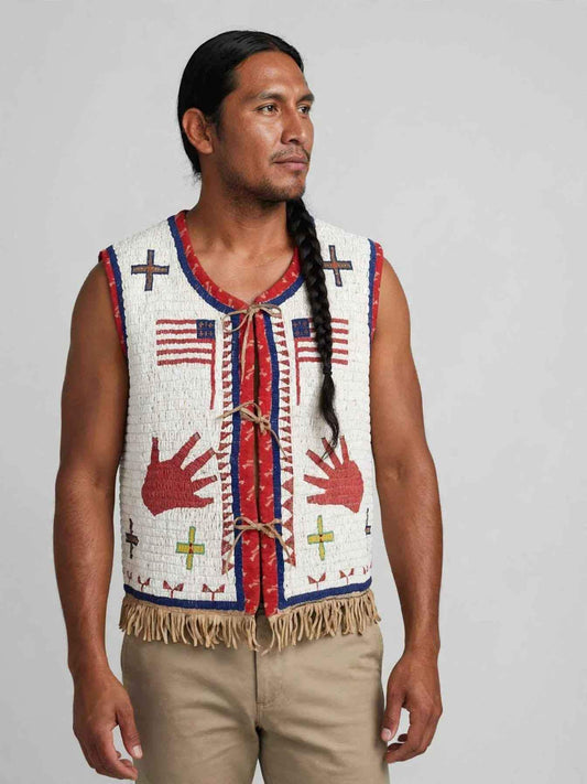 Man wearing a white beaded fringe vest with tribal patterns and red handprints.