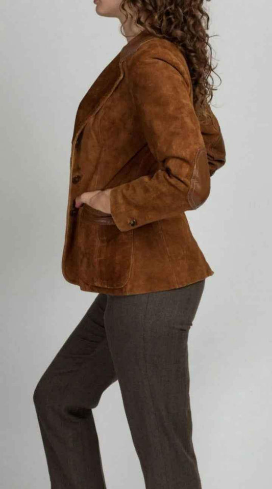 Side view of a woman wearing a Zhim Leather Creations brown suede cowboy jacket and grey trousers.