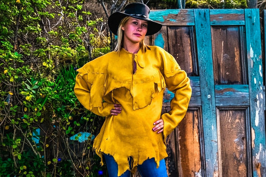 Woman wearing a mustard yellow fringe suede leather cowboy jacket with a black hat