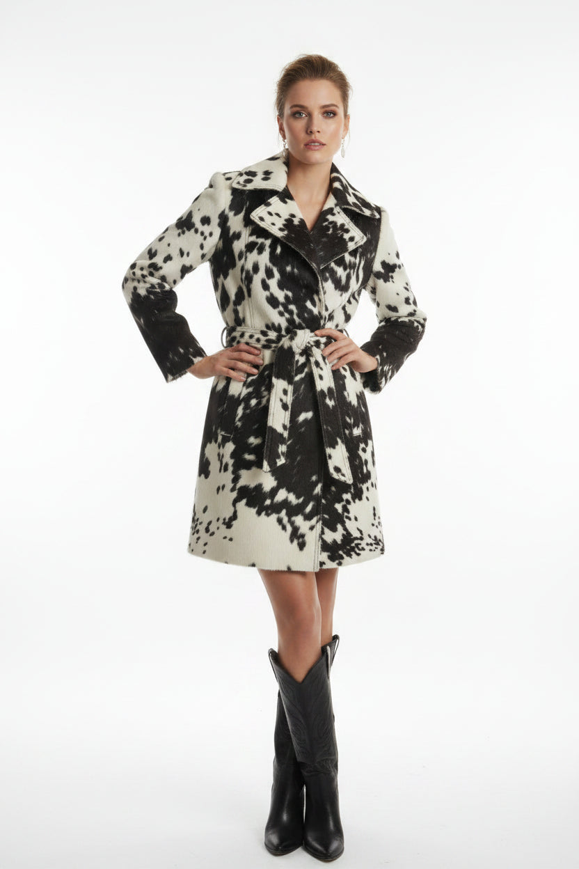 A woman's cowhide print jacket displayed on a mannequin, featuring a striking black and white cow pattern with leather elements.