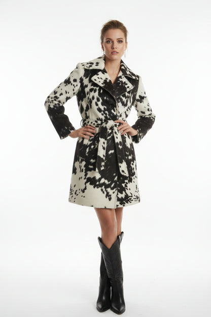 A woman's cowhide print jacket displayed on a mannequin, featuring a striking black and white cow pattern with leather elements.