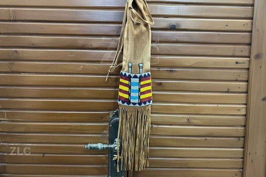 Decorative bag with colorful patterns and fringes hanging on a wooden door.