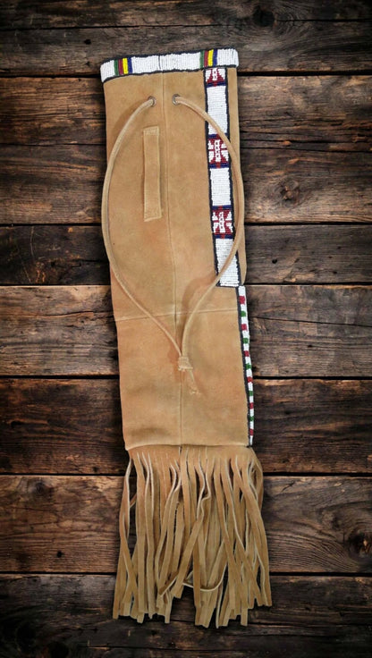 A tan suede fringed pouch with Native American style beadwork trim, displayed flat on a dark rustic wooden plank background.