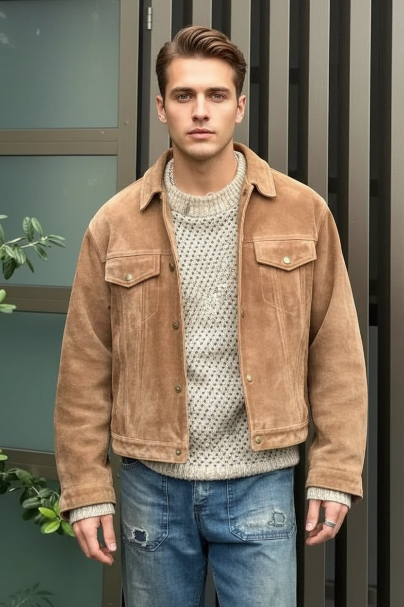 Person wearing a brown suede jacket, patterned sweater, and blue jeans standing against a neutral background.