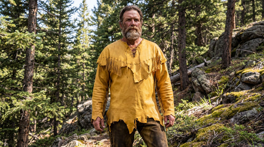 Man wearing a yellow fringed shirt in a forest setting