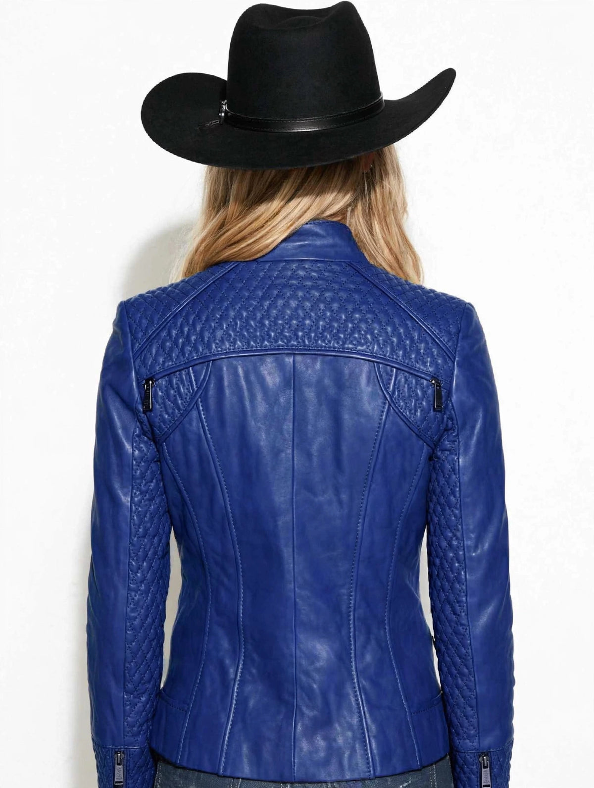 A woman shown from the back wearing a bright blue leather jacket with quilted shoulder panels and a black cowboy hat, against a plain white background.