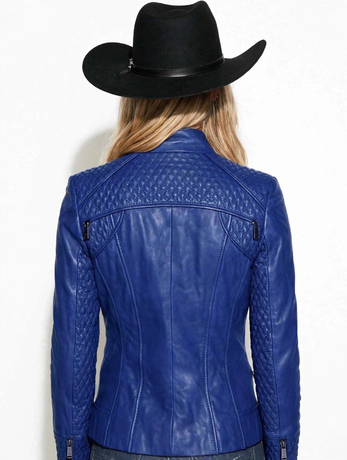 A woman shown from the back wearing a bright blue leather jacket with quilted shoulder panels and a black cowboy hat, against a plain white background.