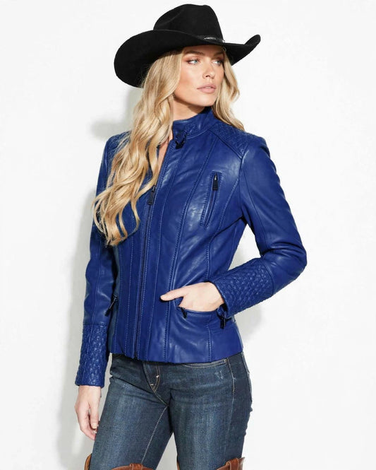 A woman wearing a royal blue lamb leather motorcycle jacket with quilted sleeve details, a black cowboy hat, and blue jeans, photographed against a plain white background.
