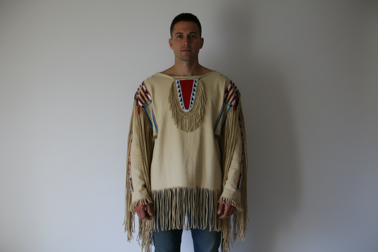Man wearing a traditional fringed garment against a plain background