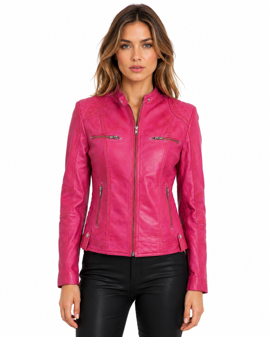 A woman modeling a bright pink faux leather motorcycle jacket with silver zippers, paired with black pants, against a plain white background.