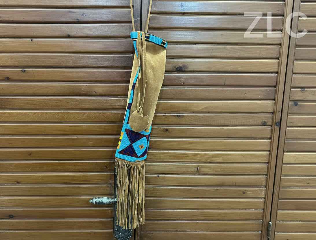 Traditional Native American saddle bag with fringes on a wooden background, featuring the brand 'ZLC'.