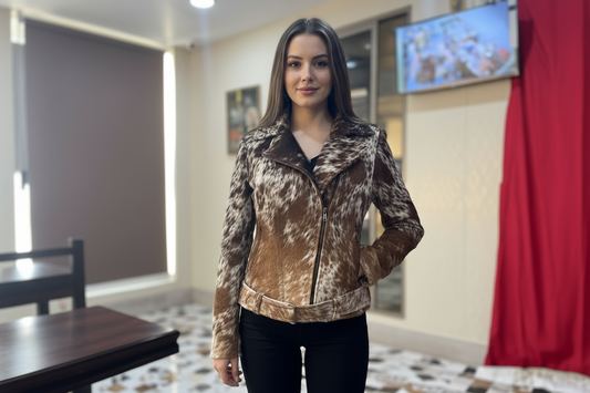 Woman wearing a patterned jacket in an indoor setting with a table and red curtain.