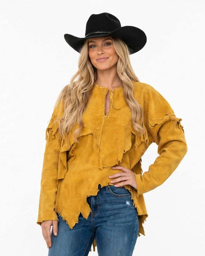 A woman modeling a mustard yellow suede fringe top with a split neckline and a black cowboy hat, paired with blue jeans, against a plain white background.