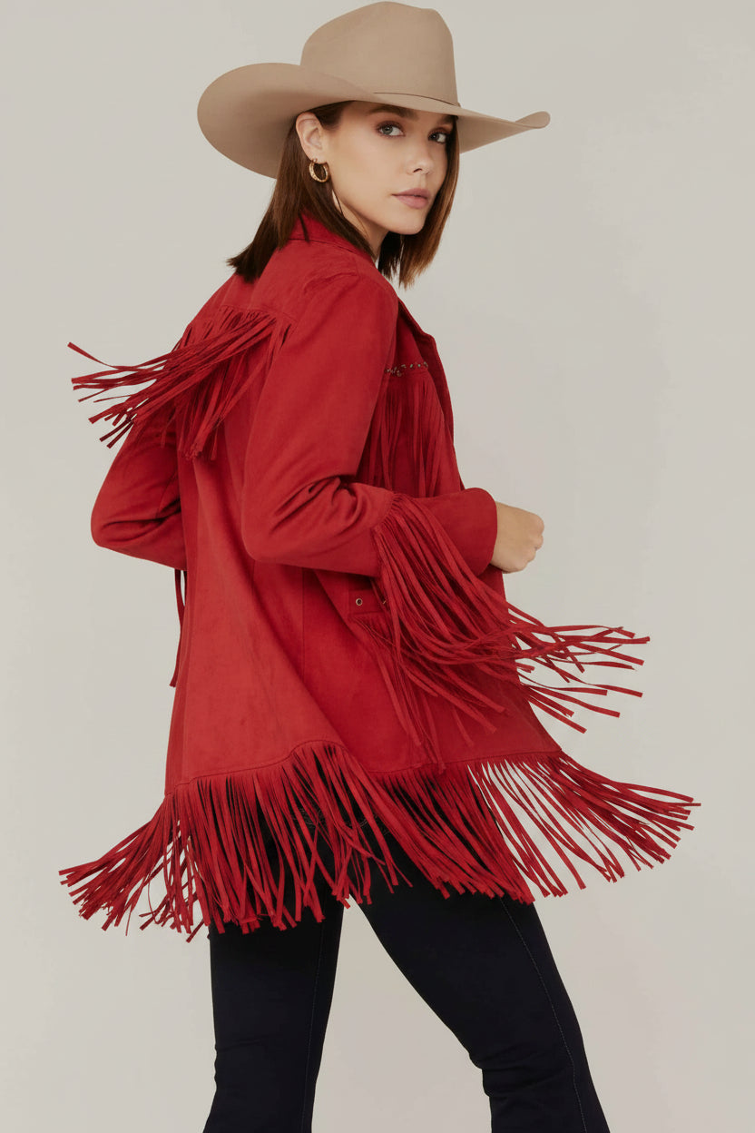 Person wearing a red fringed jacket and beige cowboy hat on a plain background