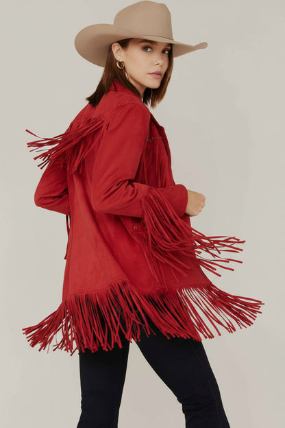 Person wearing a red fringed jacket and beige cowboy hat on a plain background