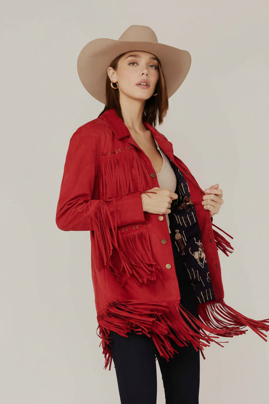 Woman wearing a red fringed jacket and beige hat on a plain background