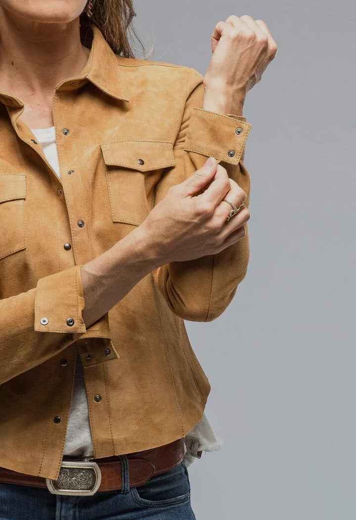 Person wearing a tan suede jacket on a gray background