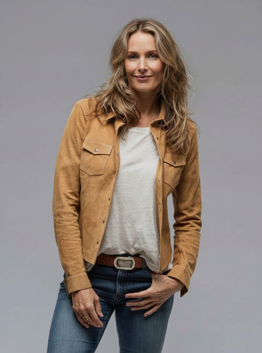 Woman wearing a tan jacket over a white shirt and blue jeans on a gray background