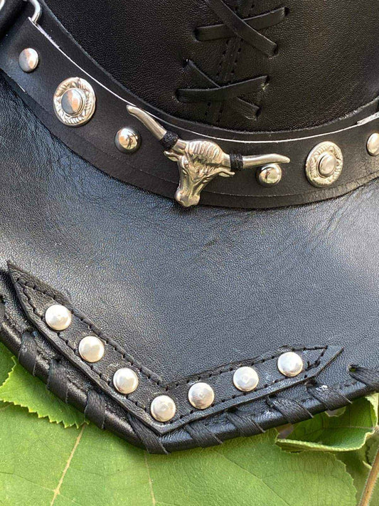 Close-up of a ZHIM LEATHER CREATIONS black leather hat featuring a silver bull skull ornament.